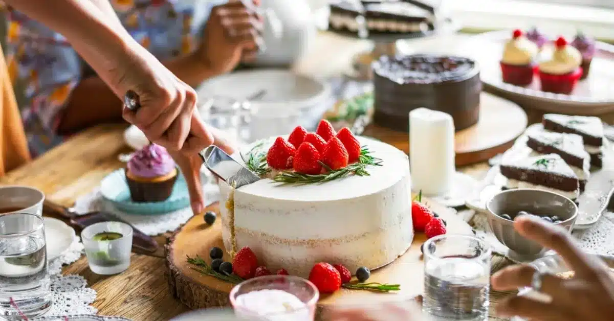 Large Gatherings together on tea party eating 2 big cakes suitable for 50 individuals