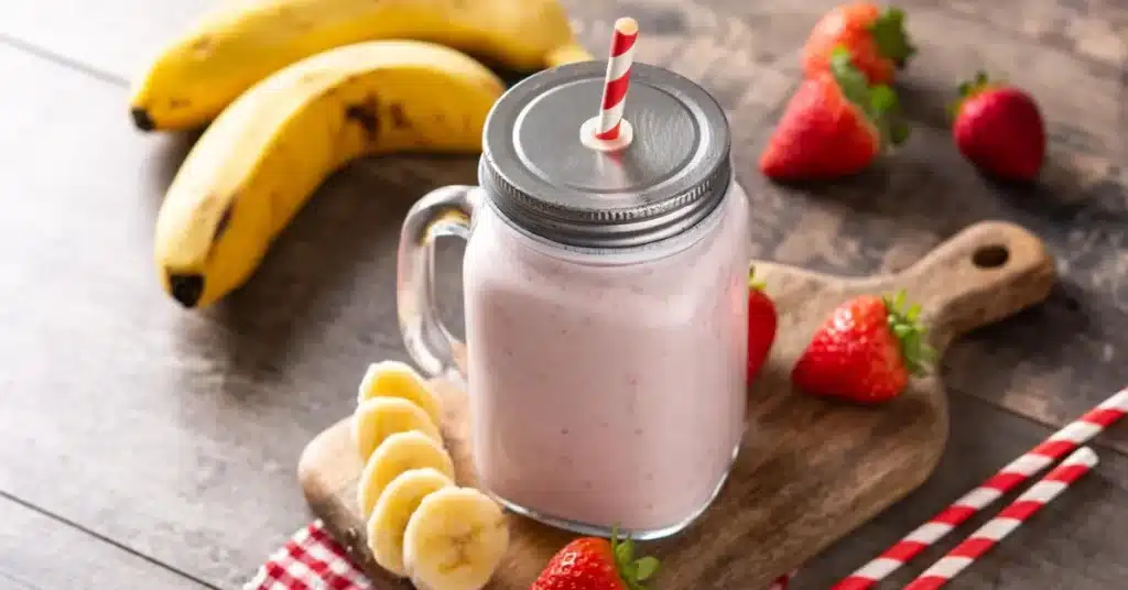 smoothie king angel food on table surrounded by strawberries and bananas.