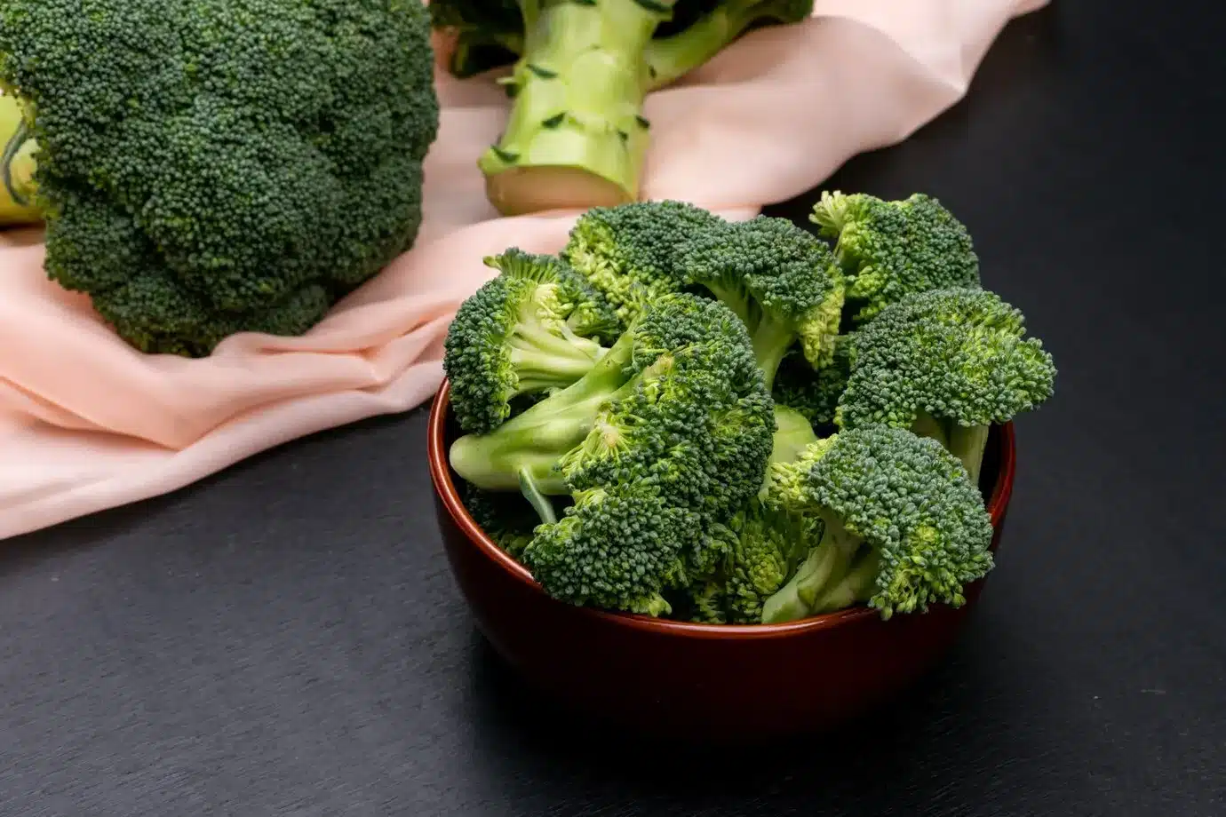 broccoli in ceramic bowl and on pink cloth