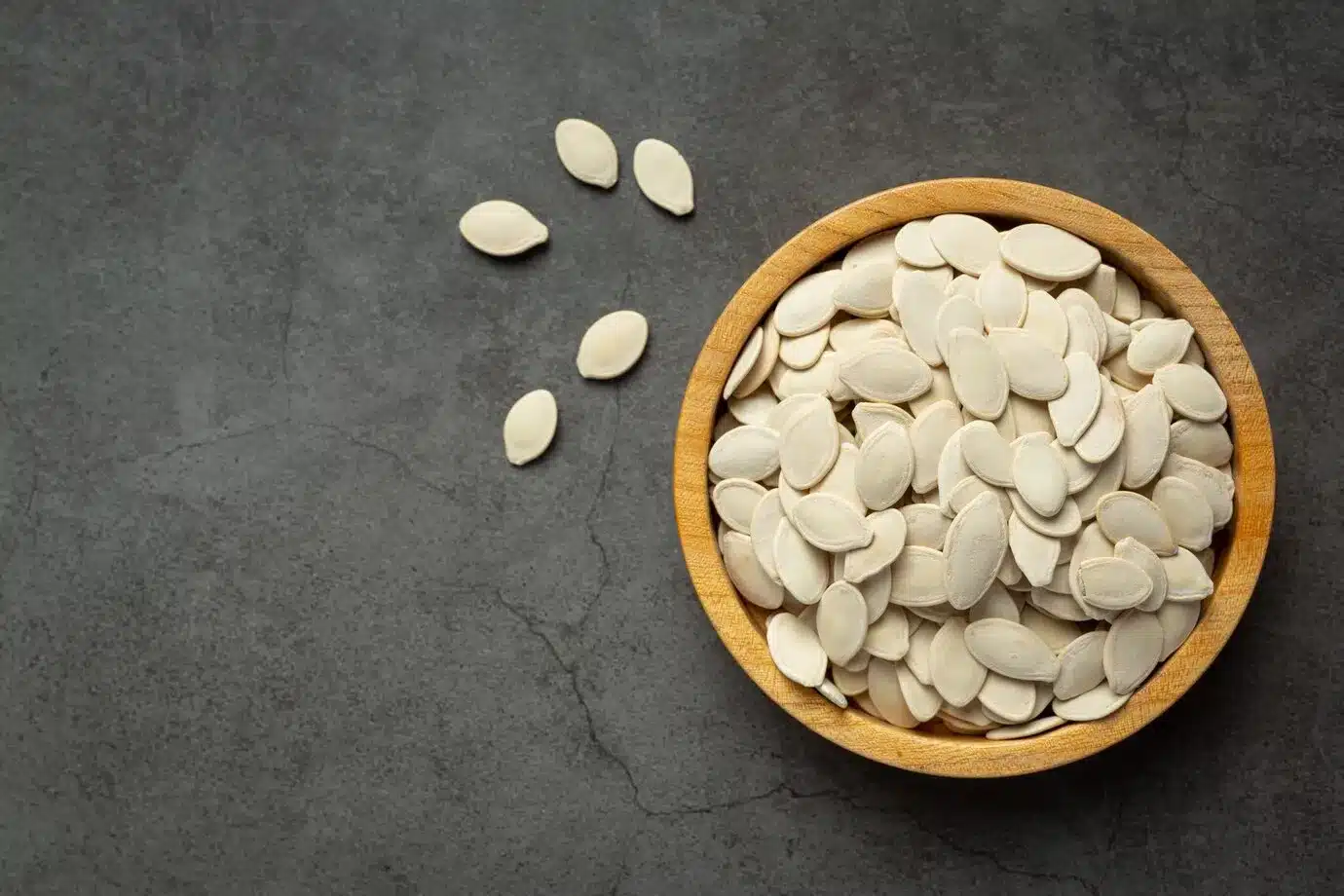 pumpkin seed put in wooden bowl on dark floor