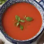 Close-up of fridheimar tomato soup recipe with basil leaves and a spoon